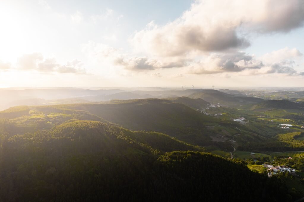 Aerial landscape of lush green hills and valleys near Gradil, Lisbon at sunset.