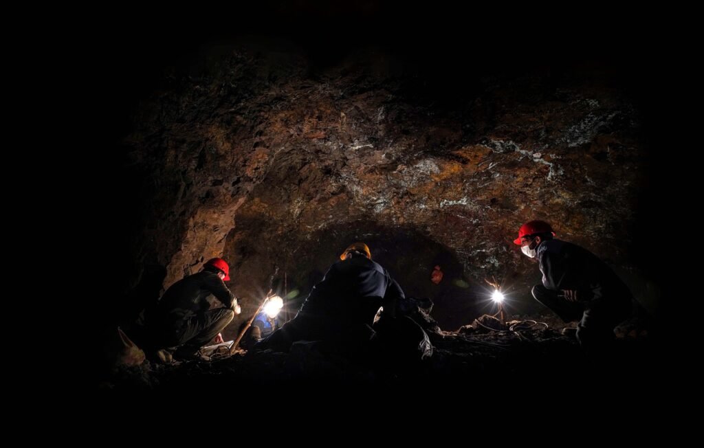 Adventurers exploring a cave in Iran at night with headlamps and hard hats.