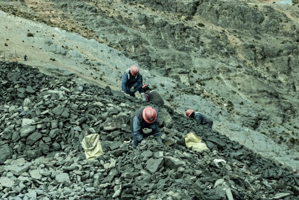 Workers with helmets collecting stones in a rocky quarry, an aerial perspective.