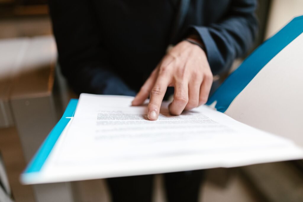 Close-up of a hand pointing at text on a business document in an office environment.